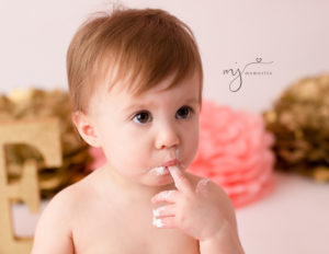 Cake smash close-up of one year old girl eating cake