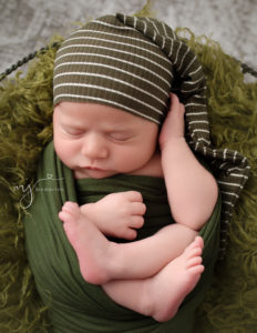 Newborn boy posed laying in a basket at his studio session in Rochester, NY