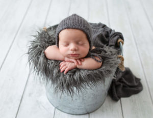 Sweet newborn posed in a bucket in our Rochester, NY studio.