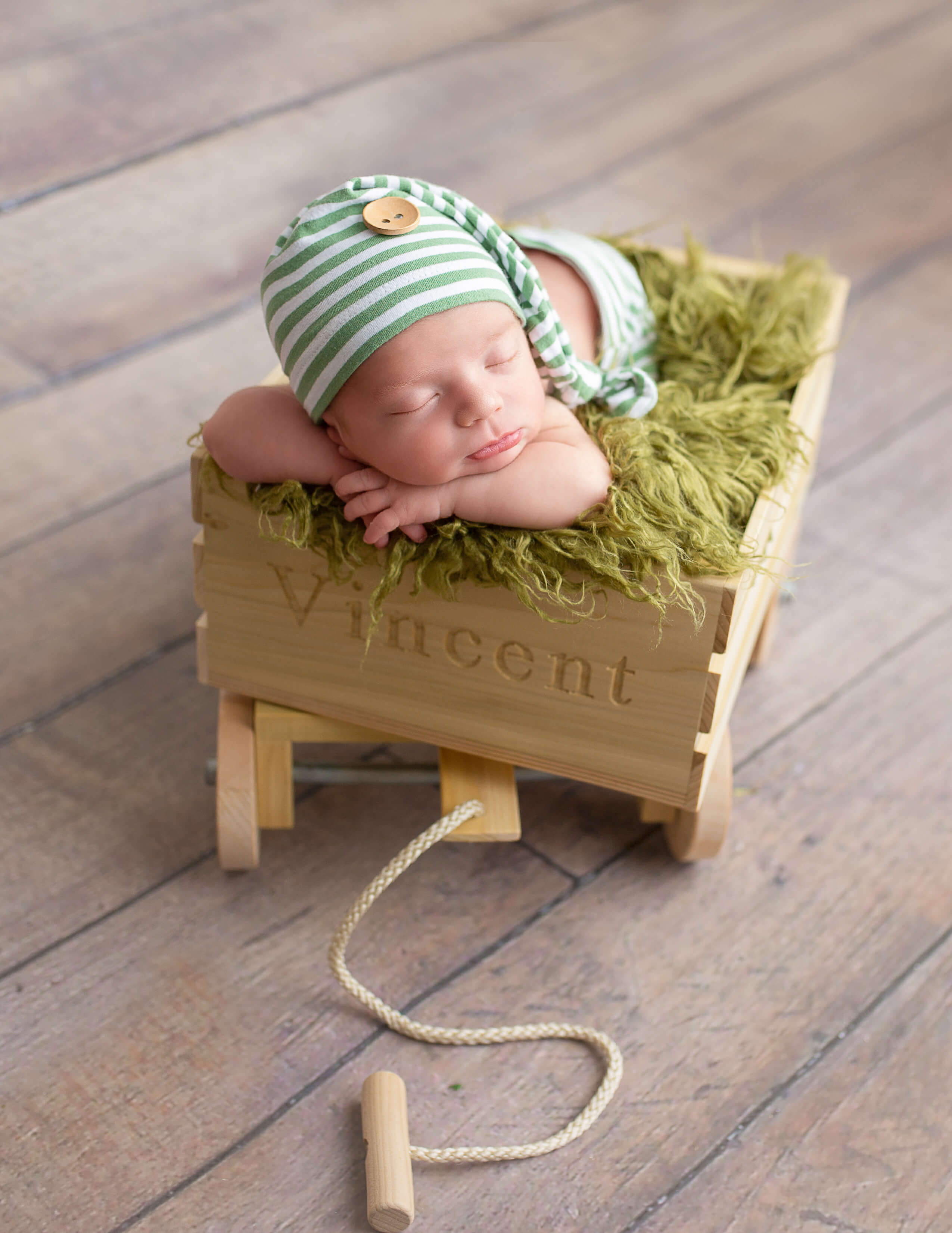 Newborn boy posed in wagon in our studio in Rochester, NY.