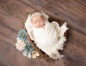 Smirking newborn girl posed at our Rochester, NY studio.