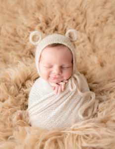 Smirking newborn boy posed at our Rochester, NY studio.