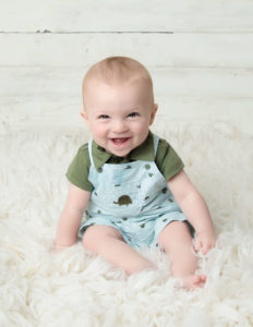 Smirking newborn boy posed at our Rochester, NY studio.