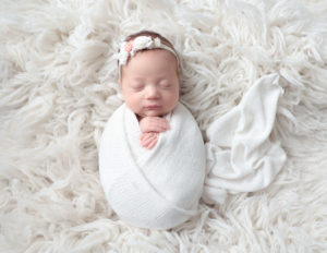 Precious newborn girl posed at our Rochester, NY studio.