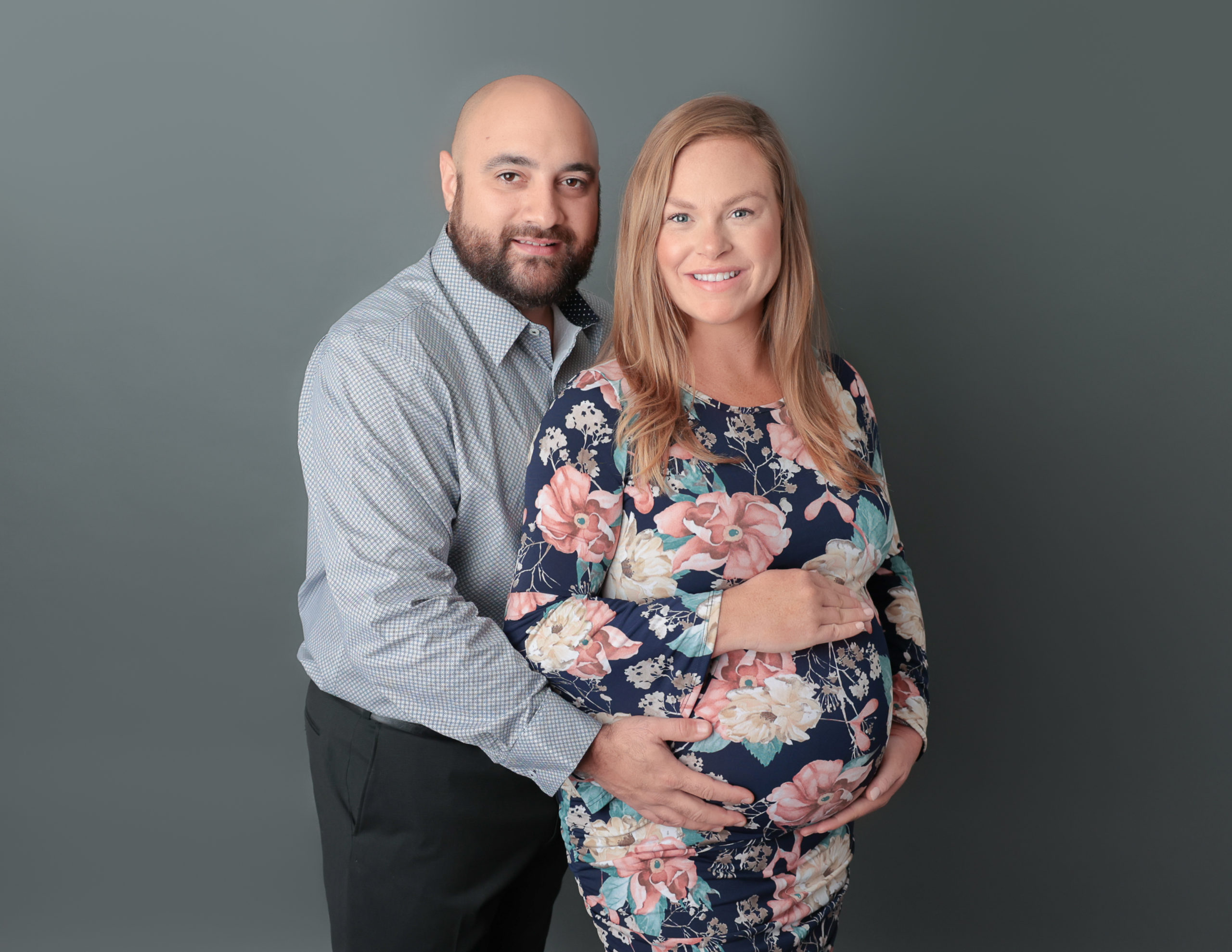 Posed couple holding her belly bump.