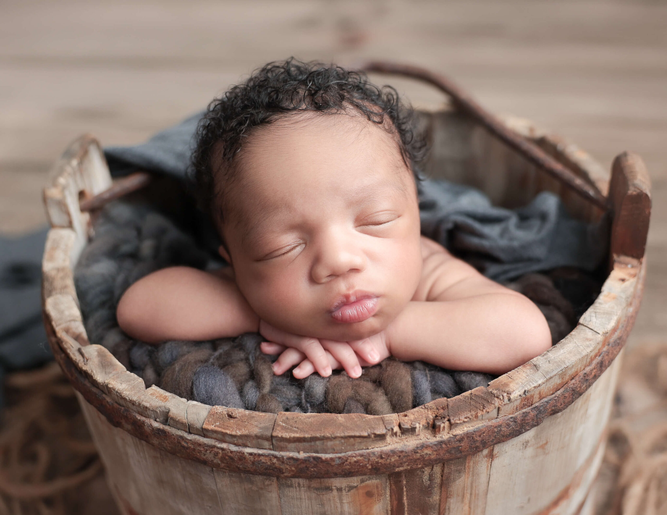 Baby boy in head-on hands pose in a bucket at our Rochester, NY studio.