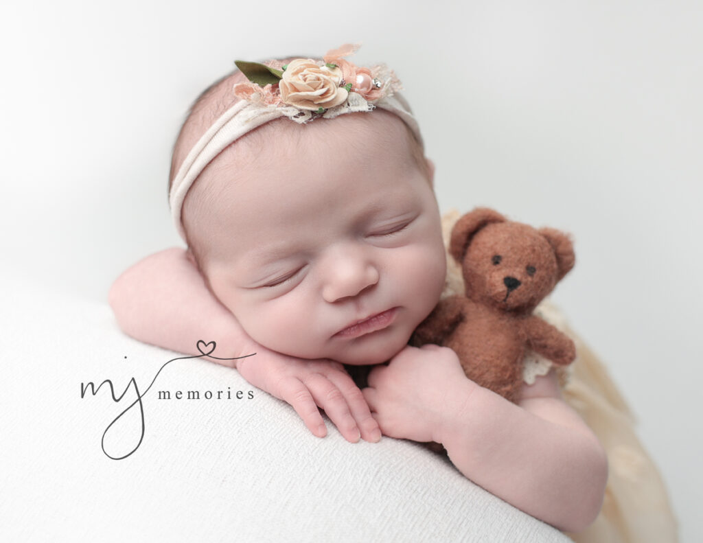 A newborn girl holding a teddy bear, Newborn Photographer.