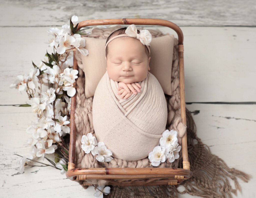 A beautiful newborn baby girl swaddled with florals, captured during a photoshoot at MJ Memories Photography studio in Rochester, NY