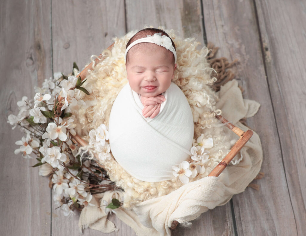 Newborn baby girl adorned with floral accents in a photography session at MJ Memories Photography studio in Rochester, NY