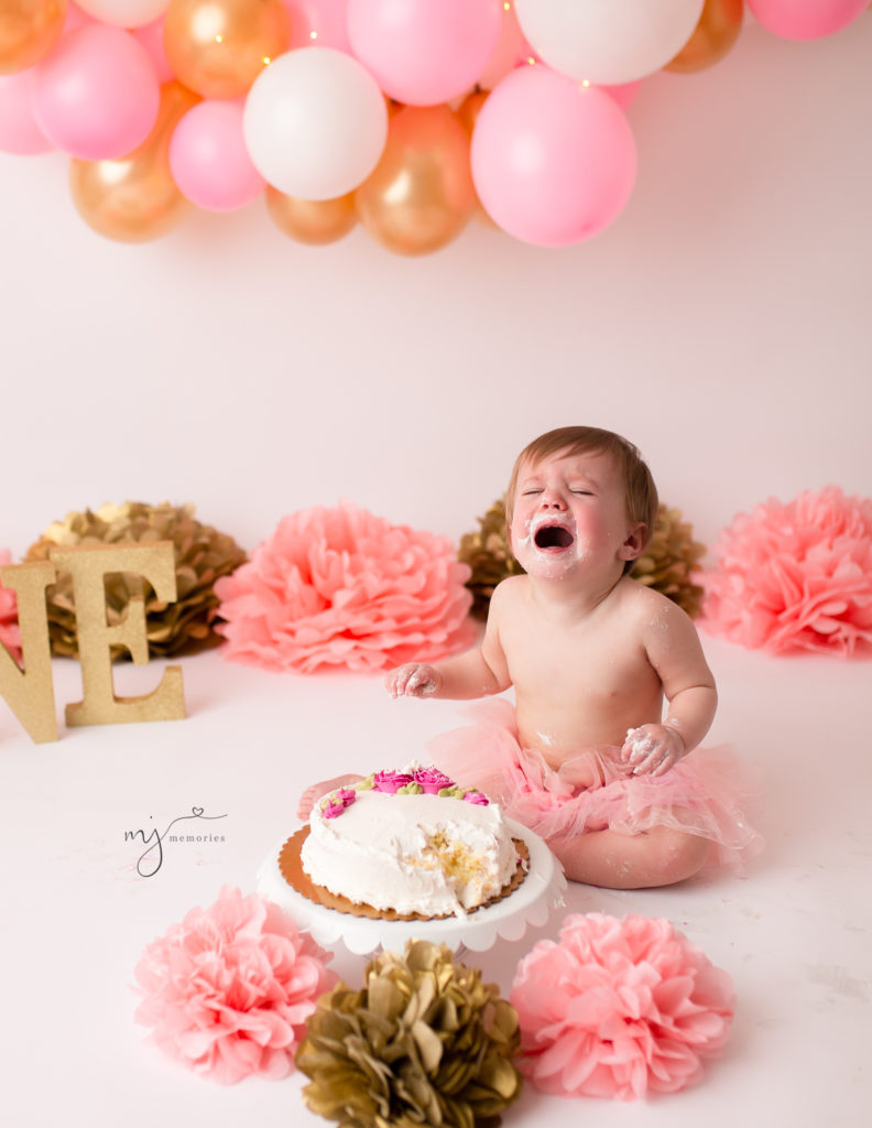 Baby girl crying at her pink and gold cake smash