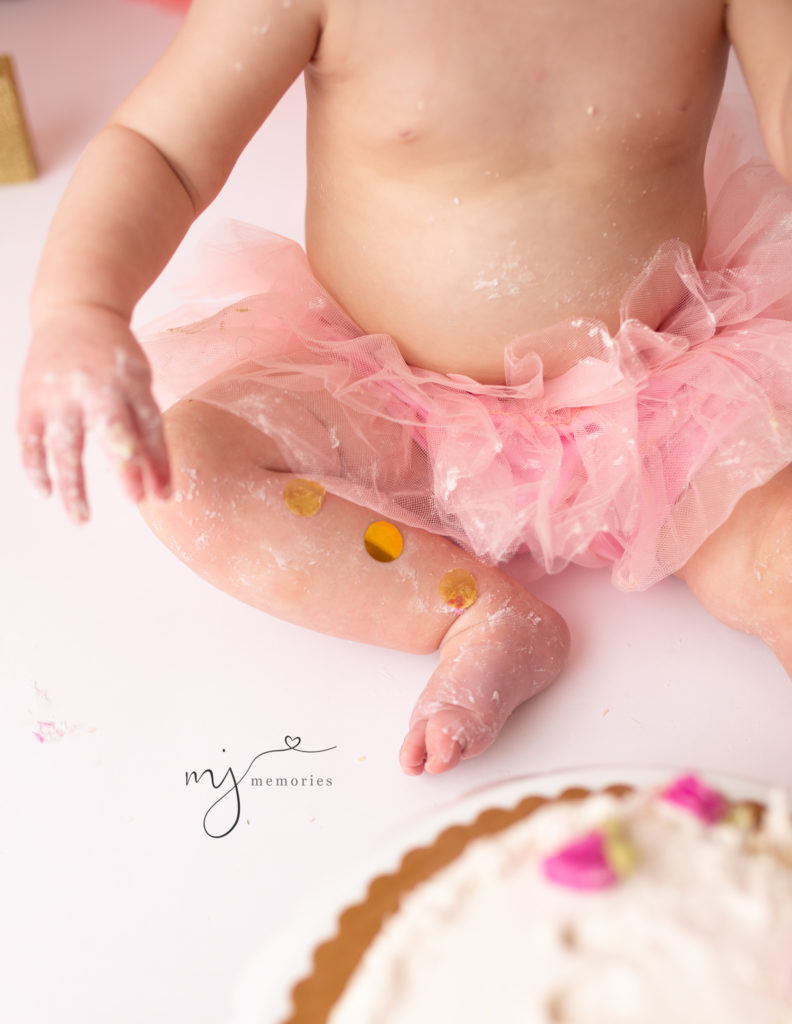 One year olds leg and foot covered in cake smash frosting and confetti