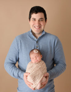 Dad holding newborn daughter in studio in Rochester, NY.