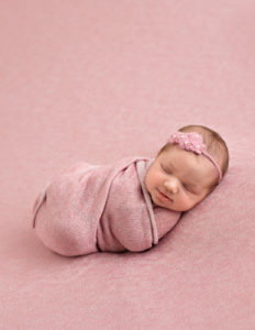 Precious newborn girl posed in studio.