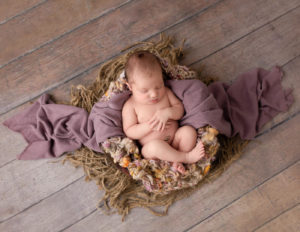 Newborn girl posed in a wooden bowl in Rochester, NY.