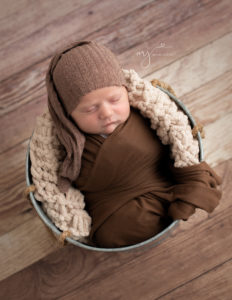 Newborn boy posed in a metal bucket in Rochester, NY photo session.