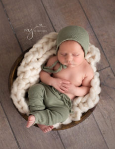 Newborn baby boy posed sleeping in a wooden bowl in our Rochester, NY studio.