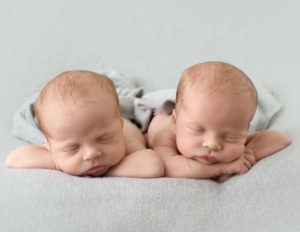 Twin newborn boys posed head on heads in our studio in Rochester, Ny.