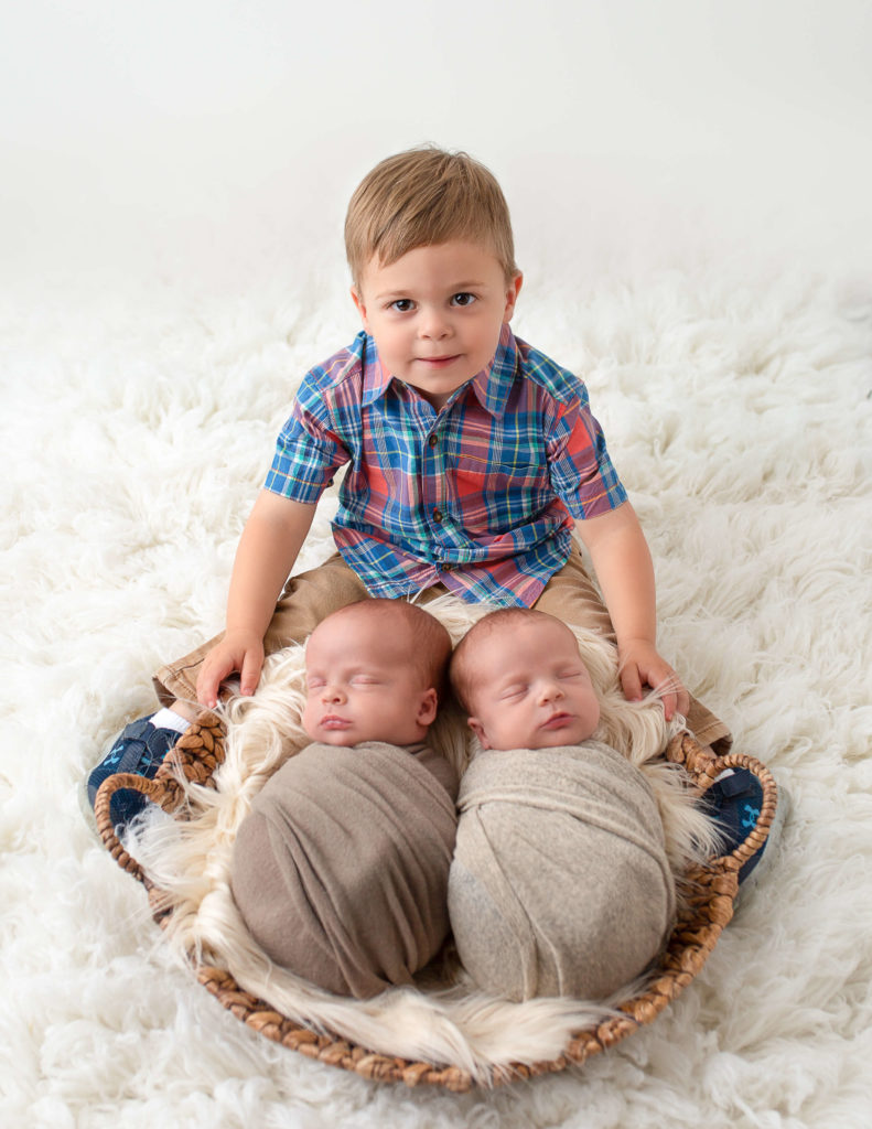Big brother posed with newborn brothers in our Rochester, Ny studio.
