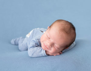 Smiling newborn boy posed in our studio in Rochester, NY.