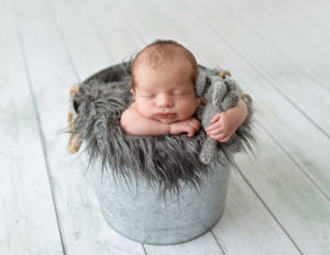 Sweet newborn posed in a bucket in our Rochester, NY studio.