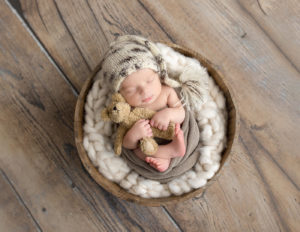 Newborn posed in a bucket in our Rochester, NY studio.