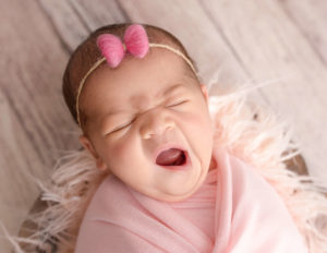 Yawning newborn baby girl posed in our studio.