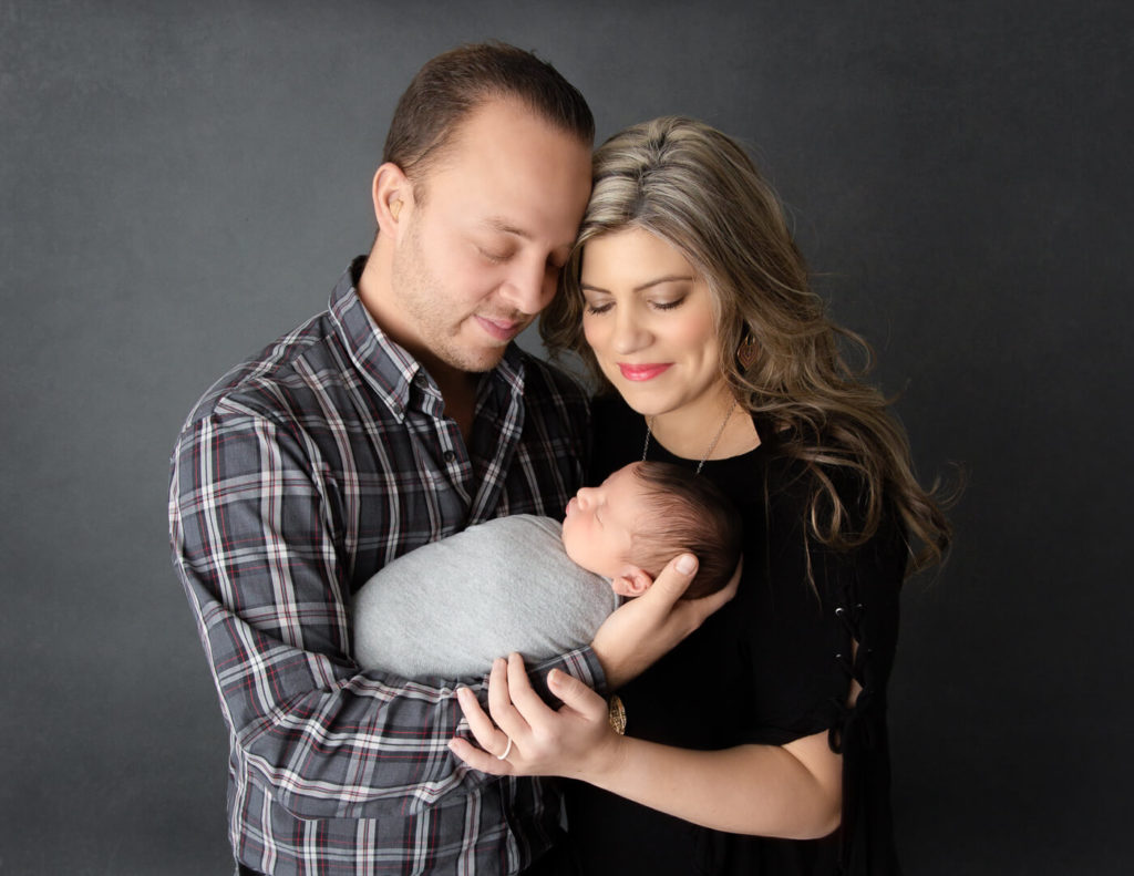 Parents with newborn posed at our studio in Rochester, NY.