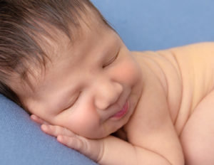Smirking newborn boy posed at our studio in Rochester, NY.