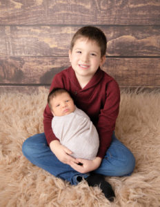 Brother and newborn posed at our Rochester, Ny studio.