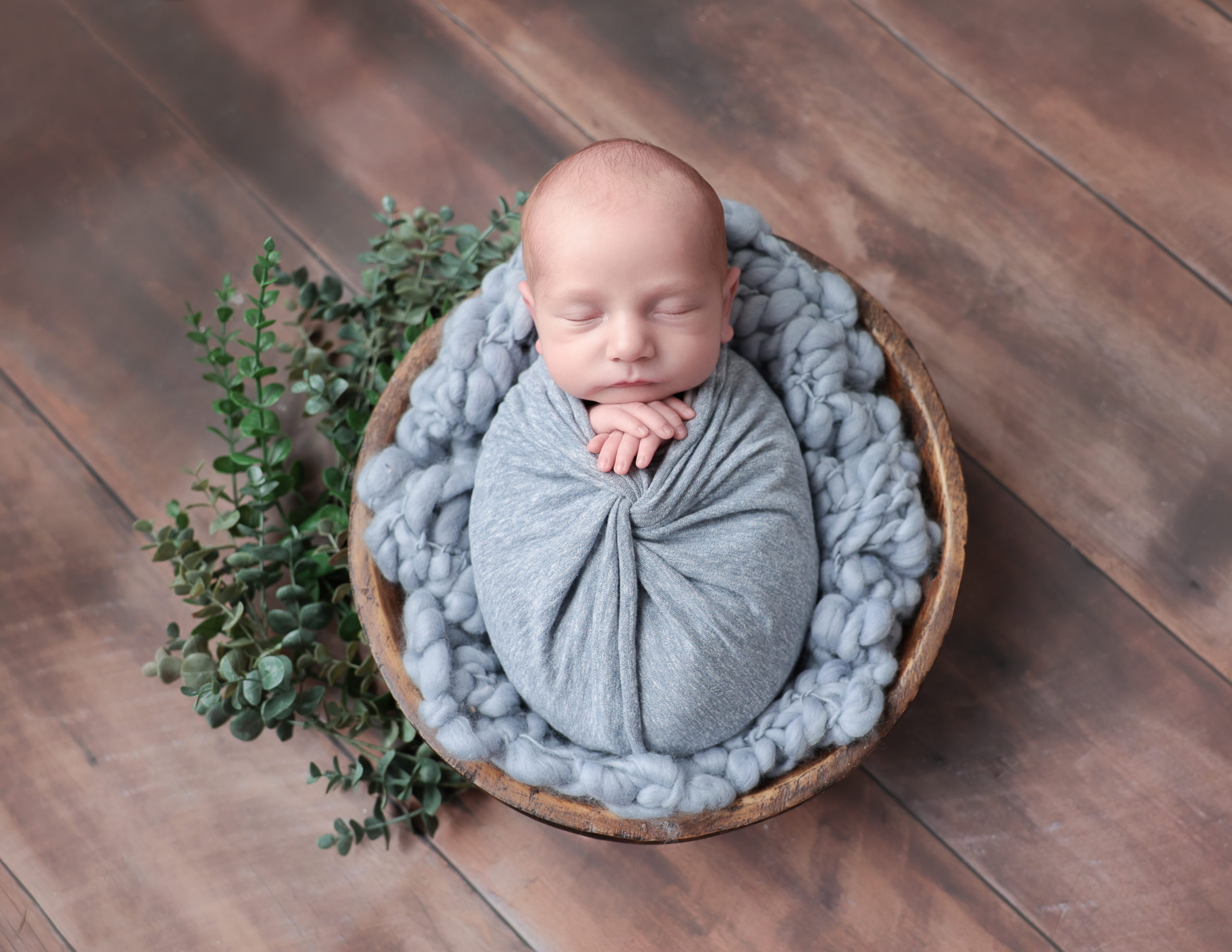 Sleeping baby boy posed in wooden bowl in our Rochester, NY studio.